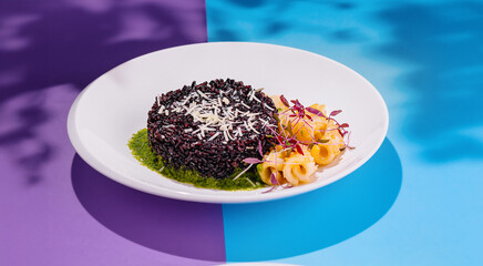 Black rice with parmesan and pasta sitting on a plate