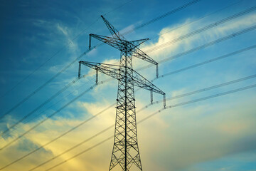 High voltage pole with electric wires against the background of evening cloudy sky.