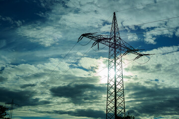 High-voltage pole against the background of the evening cloudy sky.