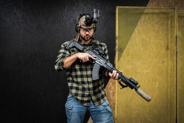 Fototapeta premium A private military in civilian clothes practices tactical shooting with night vision and a ak rifle with a suppressor at a shooting range.