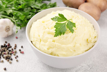 Mashed potatoes in white bowl on grey concrete background. Healthy food