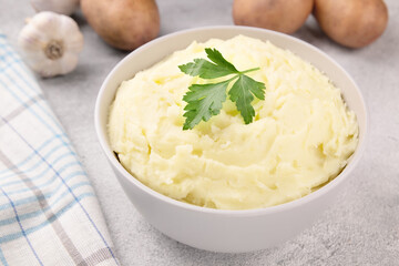 Mashed potatoes in white bowl on grey concrete background. Healthy food