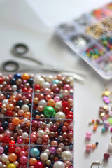 Colorful beads, letter beads, threads and other jewelry making supplies on white background. Making friendship bracelets concept. Selective focus.