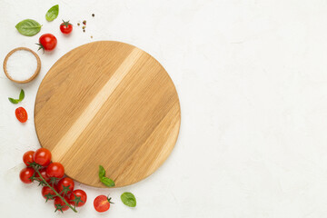 Fresh tomatoes, basil, sea salt and spices with cutting board on concrete background, top view