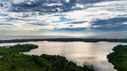 Majestic lake view in Sri Lanka during sunset. A tranquil lake reflects the colorful sky as the sun sets, surrounded by lush greenery and palm trees in Sri Lanka's serene landscape.