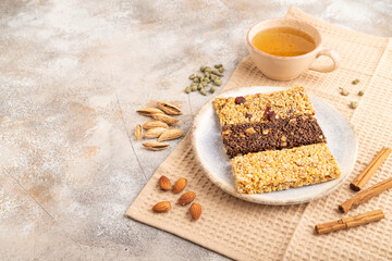 granola bars with caramel, nuts, flakes in ceramic plate on brown concrete. Side view, copy space.