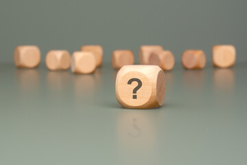 Wooden Blocks arranged on a vibrant Green Background featuring a prominent Question Mark