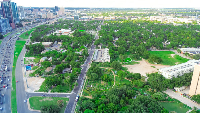 Peak hour traffic along Interstate I-35 in downtown Austin, lush green Waller Street, skyscraper, office building, tower, residential neighborhood, fast growing mixed-use development area, aerial