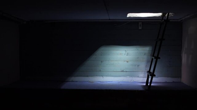 Ray of light through trap door. kerosene lamp illuminates the dark basement