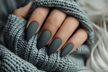 Elegant matte black nails set against a cozy sweater background in a stylish fall indoor setting