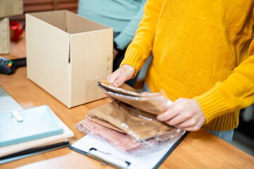 Young Entrepreneurs Packing Clothing Orders for Online Retail Business in a Modern Living Room Setting