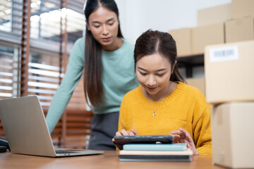 Young Entrepreneurs Managing Online Fashion Business from Home with Digital Devices and Packaging Orders for Shipment