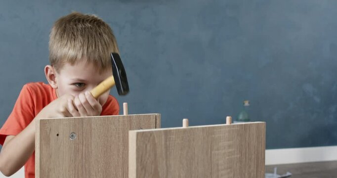 Young boy wearing an orange t shirt hammers nails into furniture while receiving guidance from his father. The activity fosters learning, bonding, and skill development in a supportive environment