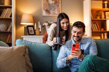 Couple surfing the net using smart phone and drinking morning coffee at home