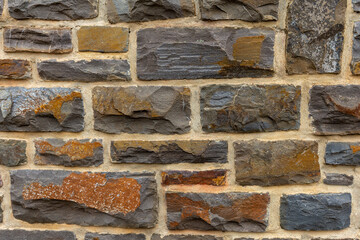 Fototapeta premium A close-up of a stone wall with brown and gray stones and tan mortar