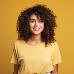 Smiling young woman in yellow shirt with curly hair. A young woman with beautiful curly hair and a bright smile wearing a casual yellow shirt