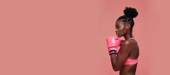 A black woman wearing pink boxing gloves in front of a pink background. Generative AI