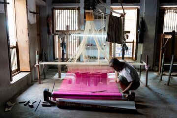 Indian man kneeling working with artisan handloom