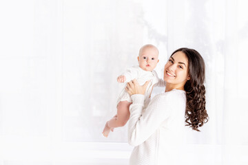 mom and baby, beautiful mother kissing newborn baby holding in his arms a home, the concept of happy loving family, lifestyle