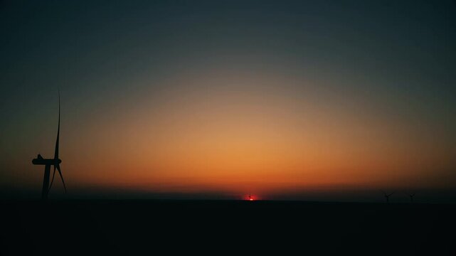 Breathtaking sunset over wind turbines in the peaceful countryside at twilight