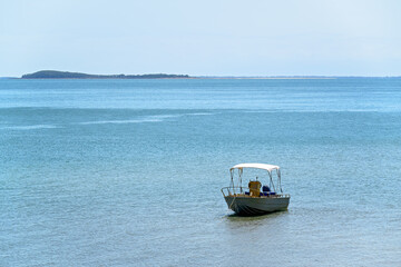 Obraz premium Boat dinghy on calm ocean water, blue cloudless sky, sunny day