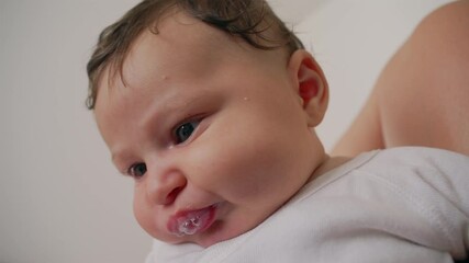 Baby with milk bubbles around the mouth, looking content and calm in a close-up view. The soft expression captures a tender and nurturing moment, reflecting love and warmth in a home setting