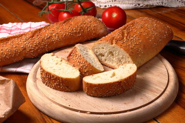 Sesame seed bread cut into slices and arranged on a wooden cutting board.