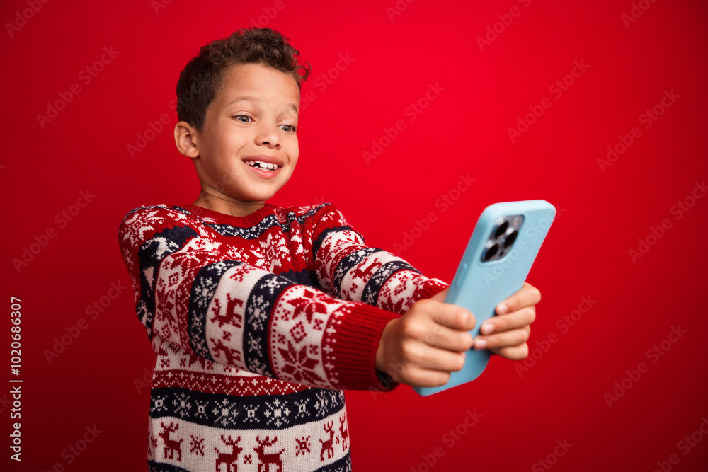 Sticker Photo portrait of charming small boy hold device excited celebrate christmas dressed knitted sweater isolated on red color background