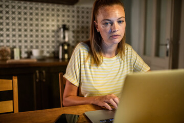 Woman stressed while working on laptop late at night