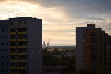 A beautiful sunset on the horizon illuminates the power plants. Steam from a cooling tower on the...