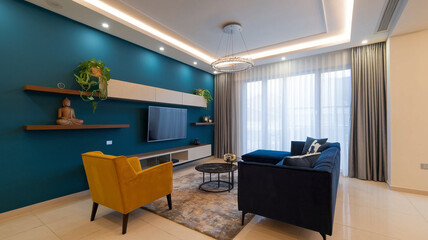 Fototapeta premium Modern Living Room with Bold Blue Accent Wall, Floating TV Unit, Yellow Armchair, Navy Sofa, and Contemporary Chandelier