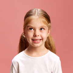 Curious girl looks up, deep in thought against pink studio background. Her playful expression sparks imagination and wonder. Concept of happiness, curiosity, positive vibes. Ad