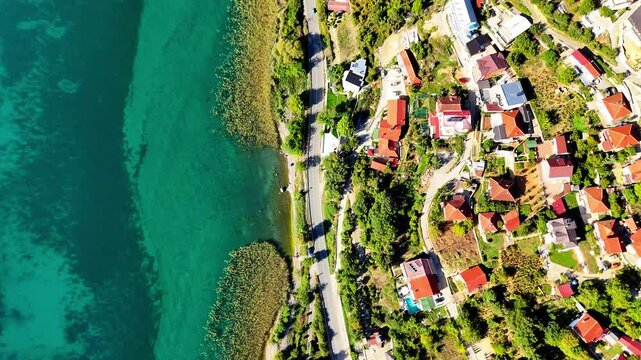 Aerial drone footage of the crystal-clear shores of Lake Ohrid and the town of Ohrid. Perfect for projects seeking stunning natural and urban landscapes with pristine waters and historic ambiance.
