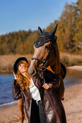 Stylish professional female jockey standing near horse. Friendship with horse. 