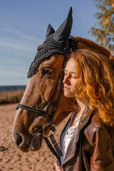 Stylish professional female jockey standing near horse. Friendship with horse. 