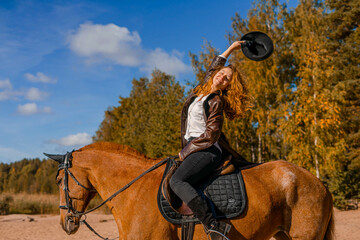 Stylish professional female jockey standing near horse. Friendship with horse. 