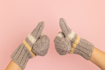 Hands showing thumbs up in woolen mittens