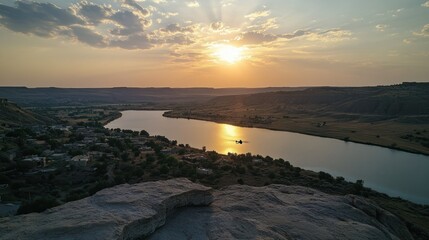 Obraz premium Sunset Over a Winding River and a Small Village in a Rocky Canyon