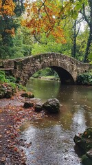 Fototapeta premium Scenic stone bridge over a tranquil stream, surrounded by lush greenery and autumn leaves, creating a serene natural landscape.