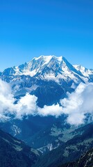 Stunning panoramic view of snow-capped mountains set against a clear blue sky, surrounded by soft white clouds.