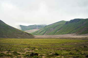 Kamchatka region. A beautiful view of green hills and majestic mountains against a cloudy sky, showcasing natures beauty