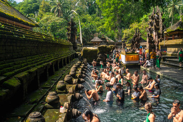 Praying in holy spring water of sacred pool at Pura Tirta Empul Temple, Tampaksiring, Bali, Indonesia