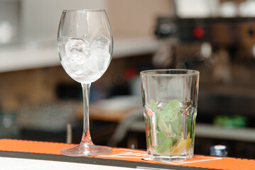 cocktail mojito ingredients, ice cubes in glass, ice and mint in glass on bar counter in bar, nightlife concept