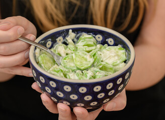 kobieta trzyma w dłoni miskę z mizerią, sałatka ze świeżych ogórków że śmietaną  © Paweł Kacperek