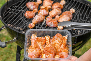 Kucharz układa podudzia z kurczaka na rozgrzanym ruszcie na grillu, 