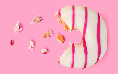 Missing piece of white chocolate and pink stripes  donut with crumbs on pink background.