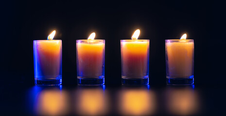 Burning candle on black background with backlight. Memorial Day.