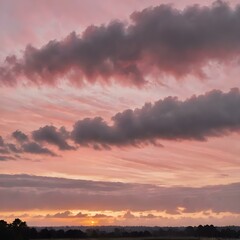 Fototapeta premium A peaceful early morning sky at dawn with low-hanging, fluffy clouds in soft shades of pink and orange, the sun just starting to peek over the horizon 