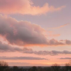 Fototapeta premium A peaceful early morning sky at dawn with low-hanging, fluffy clouds in soft shades of pink and orange, the sun just starting to peek over the horizon 
