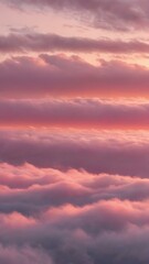 Fototapeta premium A peaceful early morning sky at dawn with low-hanging, fluffy clouds in soft shades of pink and orange, the sun just starting to peek over the horizon 